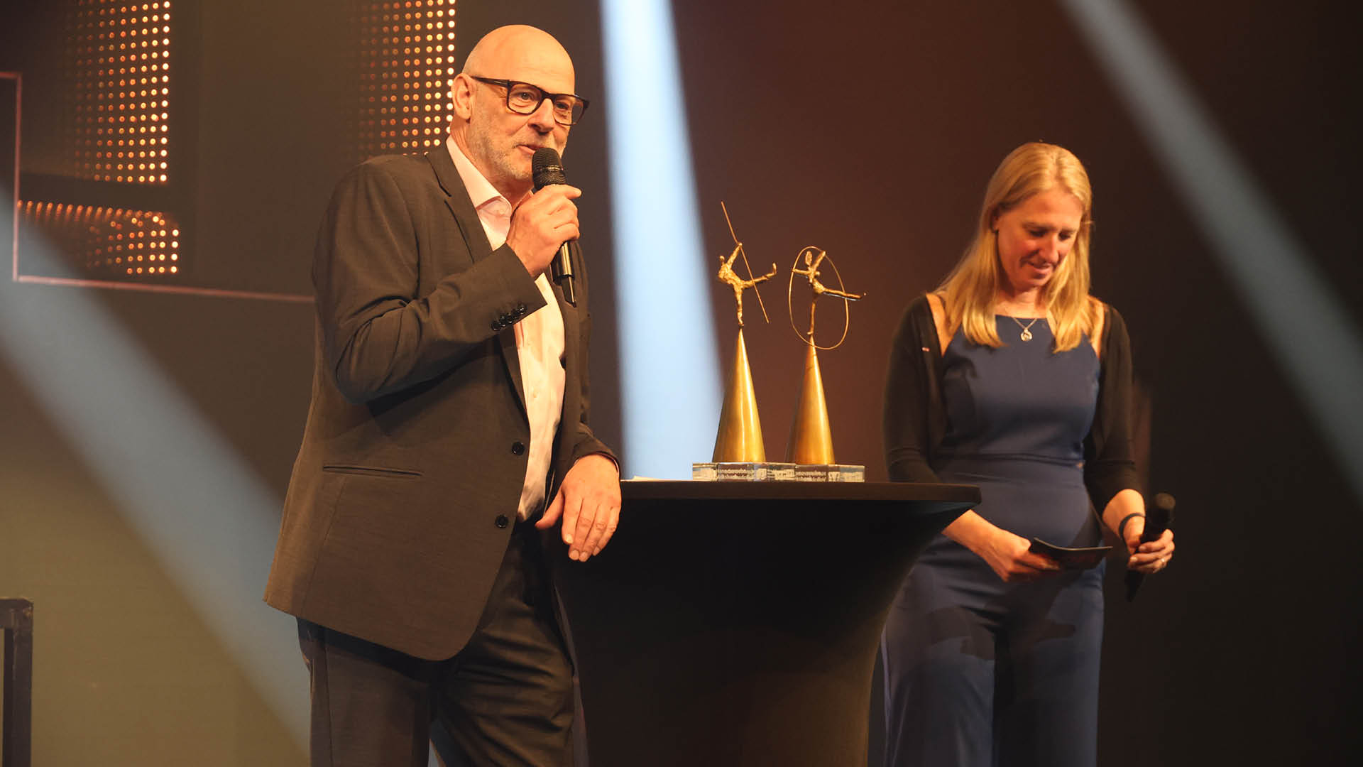 Wie immer mit viel Charme und Humor: gekonnt durch den Abend f hrten GOP-Direktorin Nadine Matzat (rechts im Bild) und Andreas Kuhnt (links). In der Mitte auf einem Stehtisch mit schwarzer Husse: die Pokale.