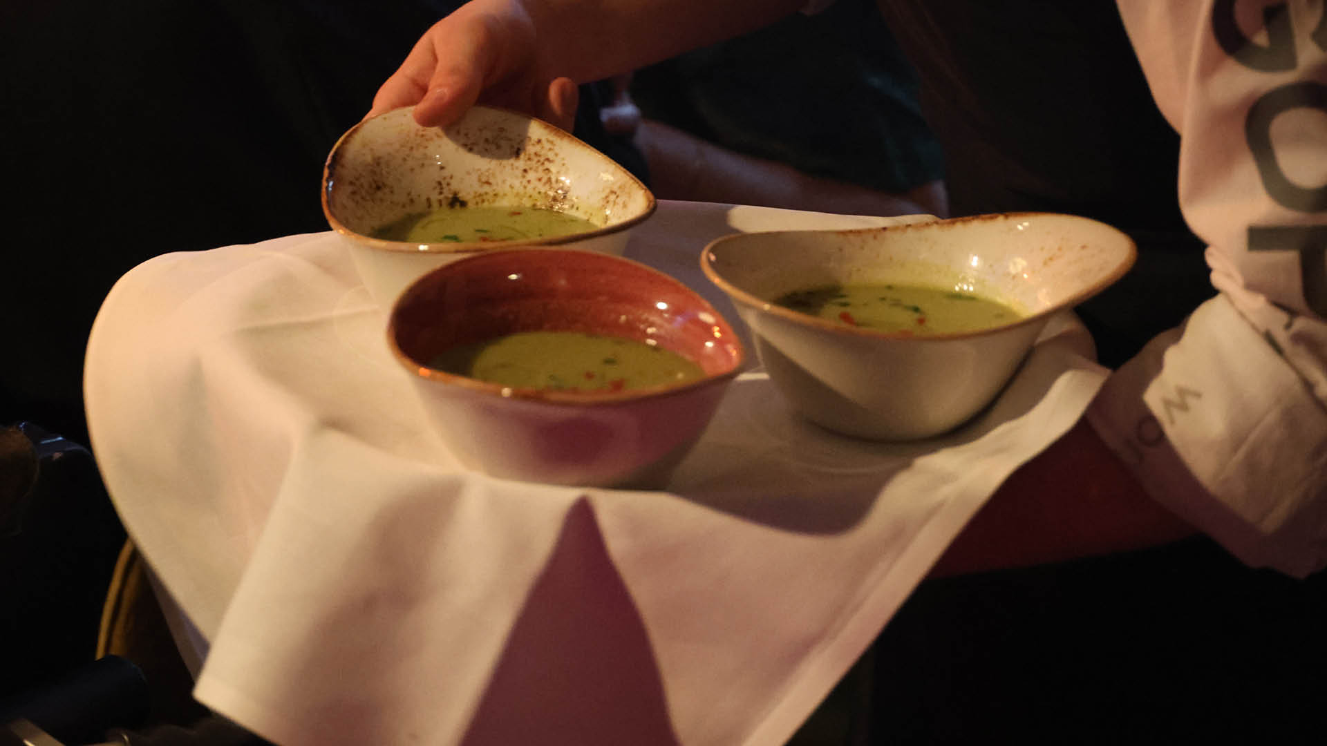 Wie immer sehr lecker: das Men des Abends charmant serviert vom GOP-Team. Zu sehen sind auf einem tablett drei Sch lchen mit der Vorsuppe, von denen eines gerade serviert wird.